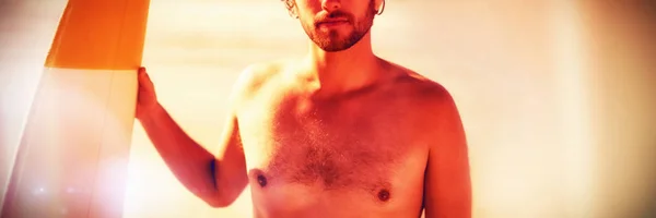 日当たりの良い日中にビーチでサーフボードを保持している上半身裸の男のポートレート — ストック写真