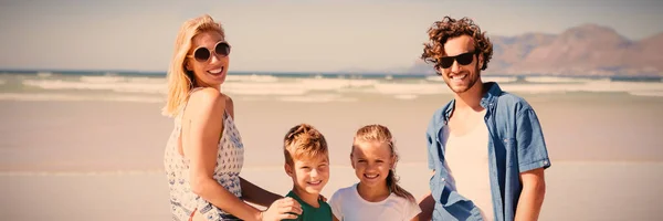 日当たりの良い日中にビーチで海岸に家族立っている笑顔の肖像画 — ストック写真