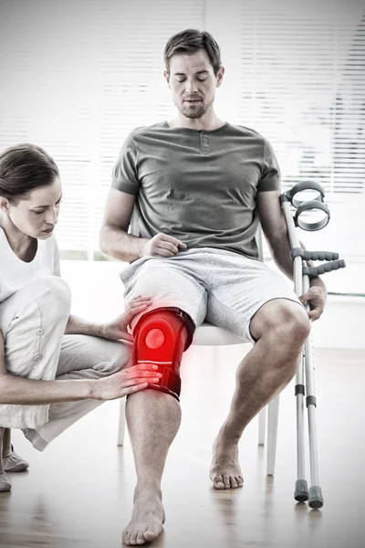 Fisioterapis Memeriksa Pria Dengan Kruk Melawan Rasa Sakit Yang Disorot — Stok Foto