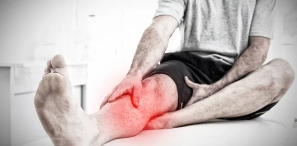 Dor destacada contra a seção baixa de um homem com as mãos em uma perna dolorosa