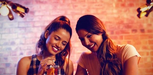 两位年轻女子在酒吧中使用手机 — 图库照片