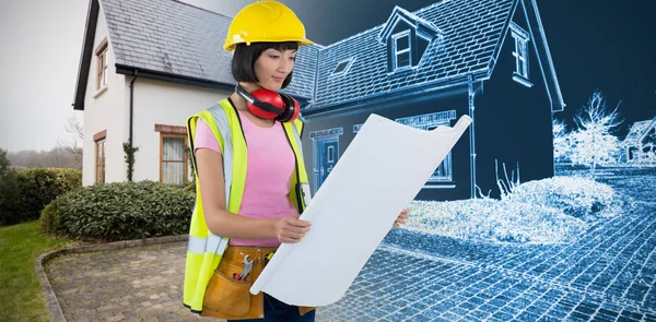 Female architect looking at blueprint against home sketch