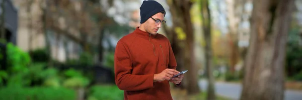 Člověk Používající Mobilní Telefon Proti Pěšina Stromů Městě — Stock fotografie
