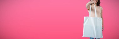 Düz pembe arka plan karşı alışveriş çantası taşıyan gülümseyen güzel kadın portresi