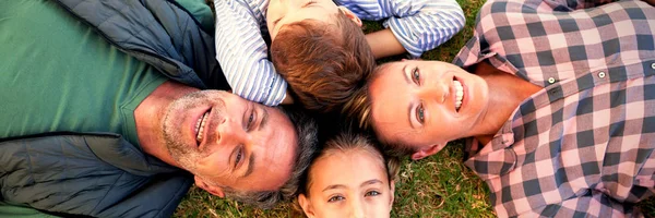 公園の芝生の上で横になっている幸せな家族 — ストック写真