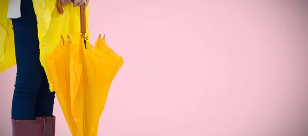 Sarı Yağmurluk Pembe Bir Arka Plan Karşı Bir Şemsiye Tutan — Stok fotoğraf