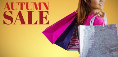 Asyalı kadın sarı arka plan karşı alışveriş torbaları ile gülümseyen