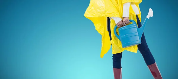 抽象的な青い背景に対して水まき缶を保持している黄色のレインコートの女 — ストック写真