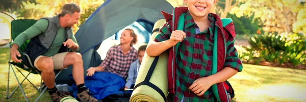 Portrait Boy Holding Rolled Mat While Family Sitting Tent — Stock Photo, Image