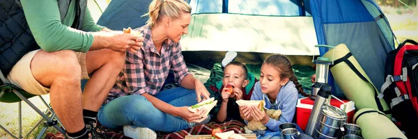 Family having snacks outside the tent at campsite