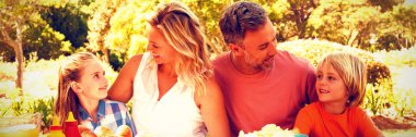 Mutlu aile güneşli bir günde Park'ta yemek yerken birbirleriyle etkileşim