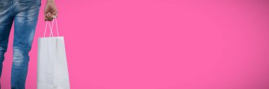 Pembe bir arka plan karşı alışveriş çantası taşıyan adam orta bölümünde
