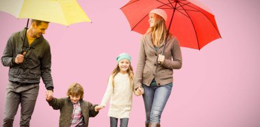 Pembe bir arka plan karşı şemsiye altında genç aile gülümseyen