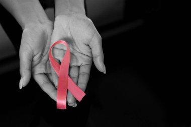 Meme kanseri siyah arka plan karşı mücadelede pembe kurdele eller göster