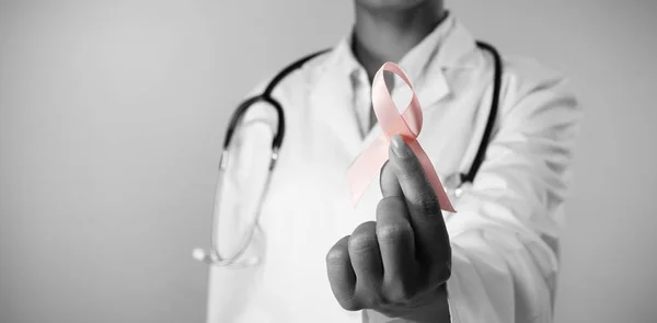 乳がん啓発のためのピンクのリボンを持って笑顔の看護師 — ストック写真