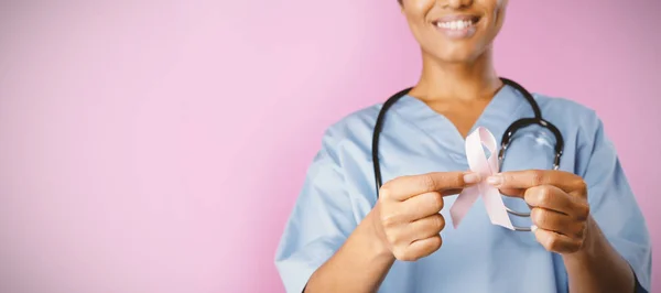 Sjuksköterska Holding Breast Cancer Awareness Rosa Bandet Med Båda Händerna — Stockfoto