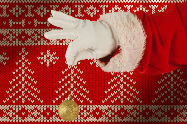 Санта Клаус Держит Рождественскую Безделушку Против Красного Бесшовного Трикотажа — стоковое фото