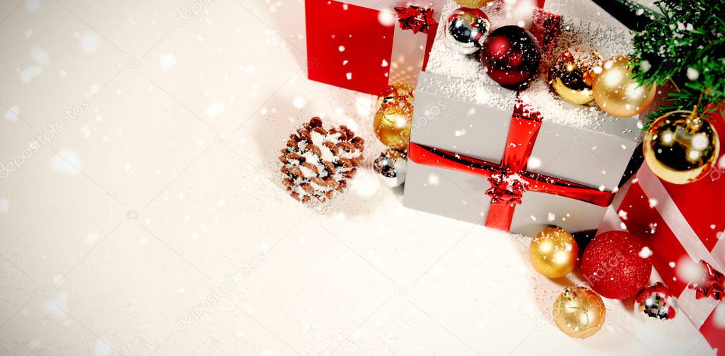 Snow falling against christmas gifts and decoration against white background