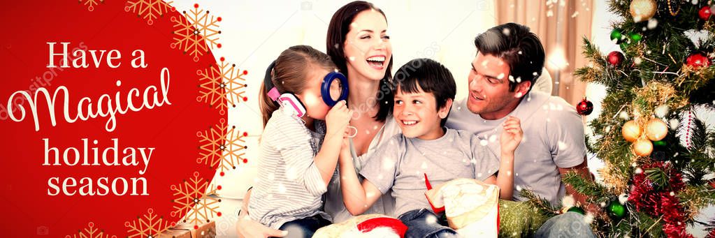 Happy family playing with Christmas gifts against white and red greetings card