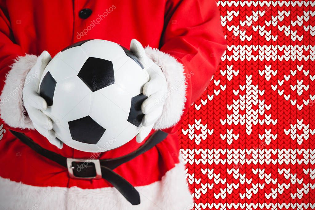 Santa claus holding a football against red knitting christmas background snowflakes