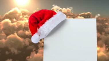 Noel Baba şapkası beyaz kartı ve bulutlar ile dijital bileşik