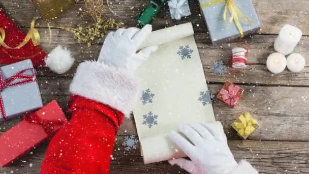 Videokomposition Mit Schnee Über Schreibtisch Mit Weihnachtsmann Enthüllt Papierrolle — Stockvideo