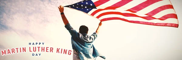 happy Martin Luther King day against low angle view of man holding american flag against cloudy sky