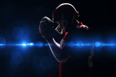 Amerikan futbolu oyuncusu rugby kask ve topu ile ayakta yan görünüm