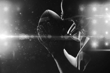 Amerikan futbolu oyuncusu rugby kask ve topu ile ayakta yan görünüm