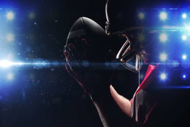 Amerikan futbolu oyuncusu rugby kask ve topu ile ayakta yan görünüm