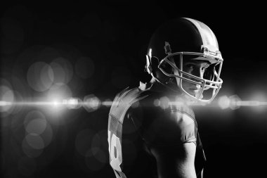 Kask ayakta siyah arka plan karşı genç Amerikan futbolu oyuncusu