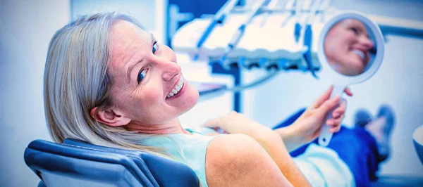 歯科医院でミラーを保持しながら笑みを浮かべて女性患者 — ストック写真