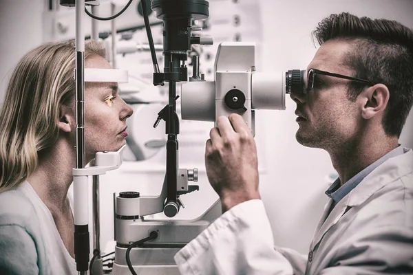 Attentive optometrist examining female patient on slit lamp in ophthalmology clinic
