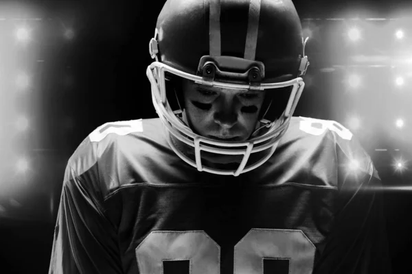 美国足球运动员站在黑色背景下戴着橄榄球头盔 — 图库照片