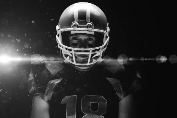 美国足球运动员站在黑色背景下戴着橄榄球头盔 — 图库照片