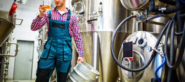 Пивоваренный завод держит бочонок и тестирует пиво на пивоваренном заводе
