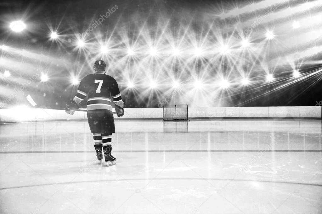 Rear view of player holding ice hockey stick against view of strong lights
