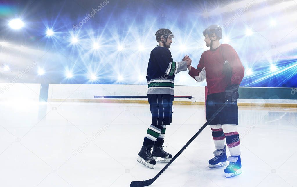 Ice hockey players shaking hands at rink against view of strong lights