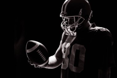 Ragbi topu siyah arka plan karşı bakarak helmat ile Amerikan futbolu oyuncusu