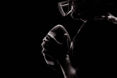 Amerikan futbolu oyuncusu rugby kask ve topu ile ayakta yan görünüm