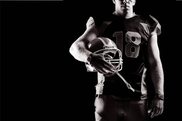 美国足球运动员在黑色背景下拿着橄榄球头盔 — 图库照片