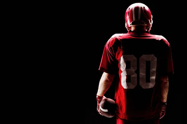 ラグビー ヘルメットとボールに立っているアメリカン フットボール プレーヤーの背面図 — ストック写真