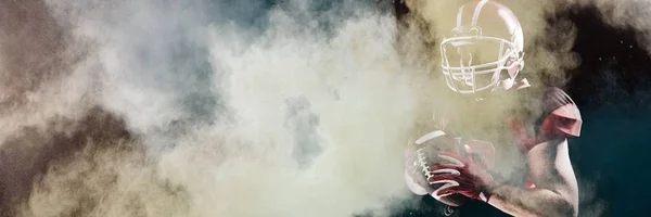 在头盔拿着橄榄球的情况下 向美国足球运动员泼粉 — 图库照片