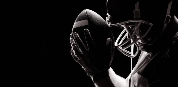 美国足球运动员拿着橄榄球头盔和球站着的特写镜头 — 图库照片