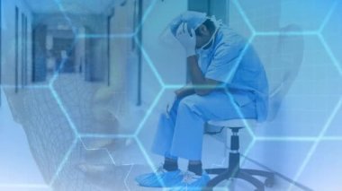 Dijital animasyon stresli doktor hastane koridorunda oturuyor. Altıgen desen ve ön planda insan arabirimi 