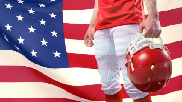 アメリカの国旗に対するラグビー ヘルメットと立っているラグビー選手のデジタル アニメーション バック グラウンドで揺れるアメリカ国旗 — ストック動画