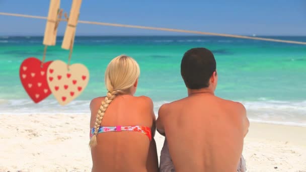 最前線で二つの心と 晴れた日にはかなり青い海と波を見てビーチのカップルのデジタル合成 — ストック動画