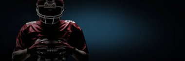Rugby kask içinde duran ve skeç ile mavi arka plan karşı ragbi topu tutan Amerikan futbolu oyuncusu