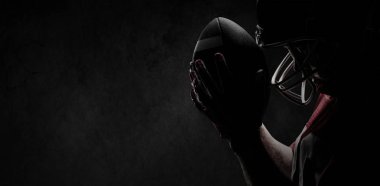Rugby kask ve beton duvar tam kare çekim top ile ayakta Amerikan futbolu oyuncusu
