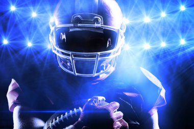 Amerikan futbolu oyuncusu ragbi topu tutan kask içinde karşı güçlü mavi ışıklar görünümünü